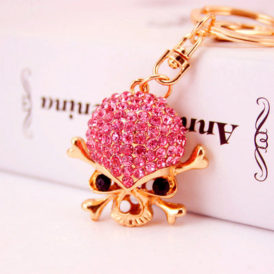 Close-up of a pink rhinestone skull charm attached to a gold-tone keyring.