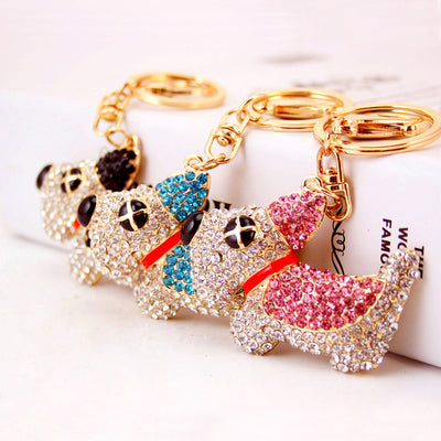 Three dog-shaped keychains in black, blue, and pink rhinestones are arranged together.