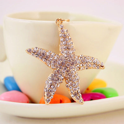 Front view of the rhinestone-covered starfish charm against a pale cup.