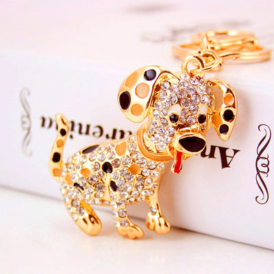 Close-up front view of a rhinestone spotted dog charm beside a white box