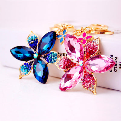 Pink and blue flower keychains sit side by side with faceted and rhinestone petals.