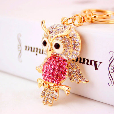 Close-up of a gold-tone owl keychain with a pink stone-covered belly.