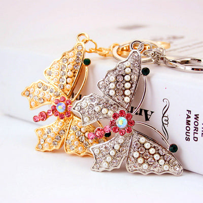 Gold- and silver-tone butterfly keychains displayed together with rhinestones and pearl-like beads.