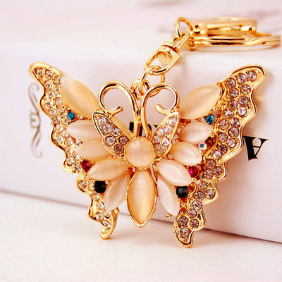 Close view of a gold tone butterfly keychain with cream cabochons and clear rhinestones