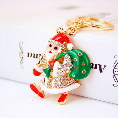 Close-up front view of a rhinestone Santa ornament carrying a green sack and attached to a split ring.