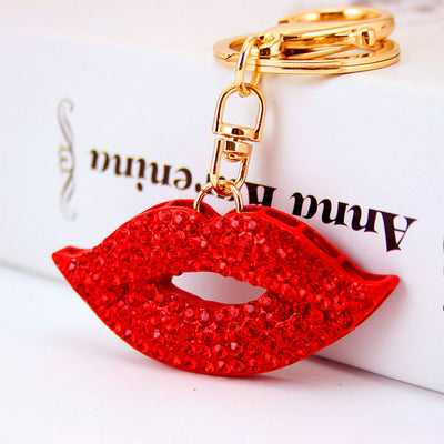Red stone-covered lips charm hanging from gold-tone key hardware on a white box