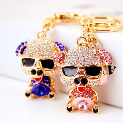 Pink and blue rhinestone pig keychains displayed together on a white surface.