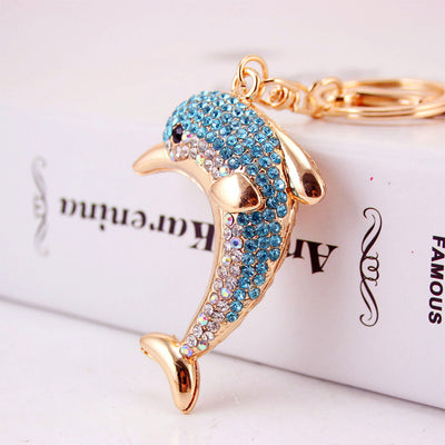 Close-up of a blue and clear rhinestone dolphin attached to gold-tone key hardware.