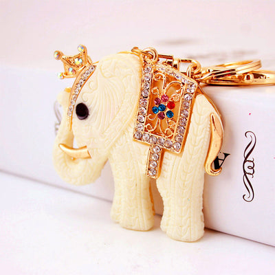 Crowned ivory white elephant keychain resting beside a white box.