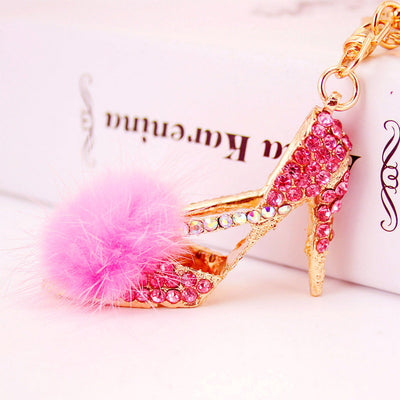 Close-up of a pink rhinestone high heel charm with a pink fluffy pom-pom.