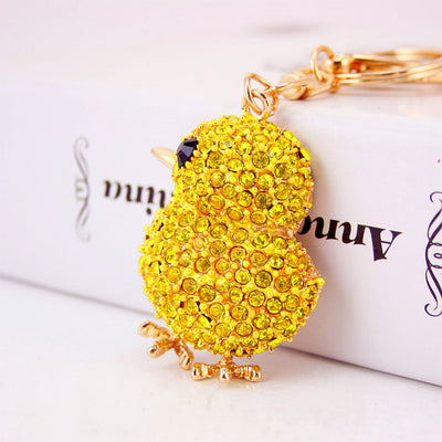 Close-up front view of the yellow stone-covered chick charm beside gold-tone keychain hardware.