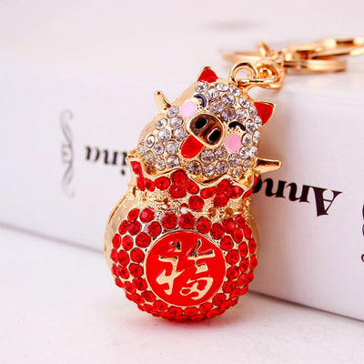Close-up of the red rhinestone pig charm showing the gold-tone Fu medallion.