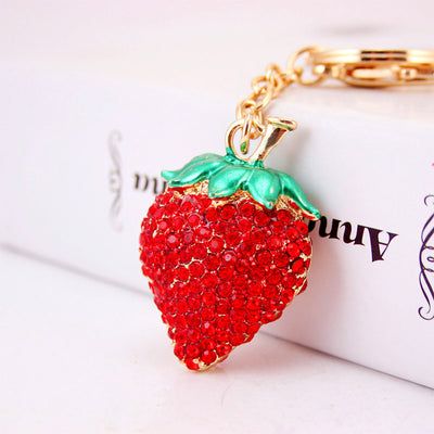 Close-up of the red rhinestone strawberry charm beside a white box.