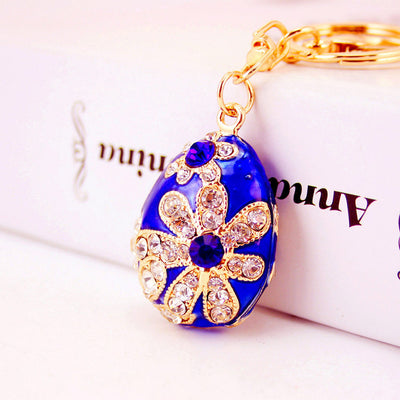 Close-up of a blue egg keychain decorated with clear rhinestone flowers.