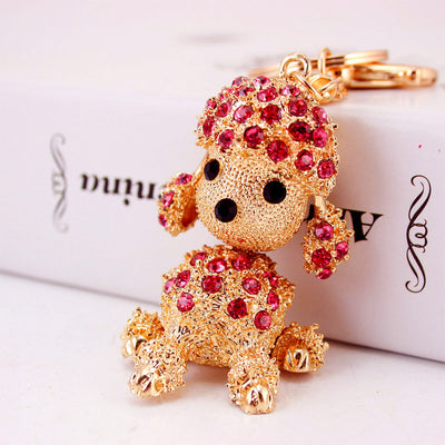 Close-up of a gold-tone seated dog keychain decorated with pink rhinestones.