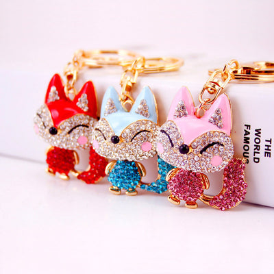 Three jeweled fox key rings in red, blue, and pink stand side by side.