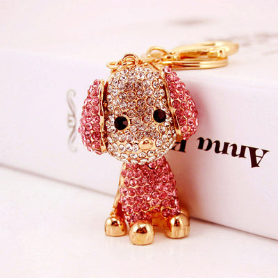 Pink rhinestone sitting dog keychain shown upright beside a white box.