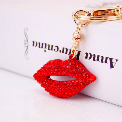 Close-up of a red rhinestone lips charm attached to gold-tone keychain hardware.