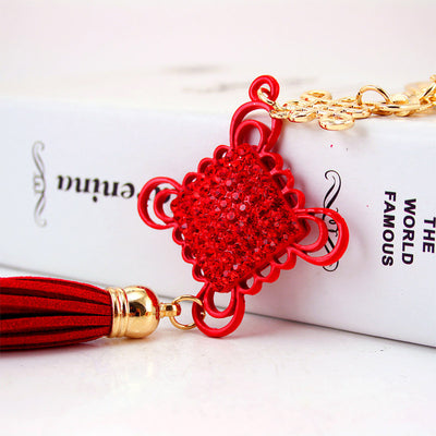 Close-up of the red rhinestone knot centerpiece and tassel beside a book.