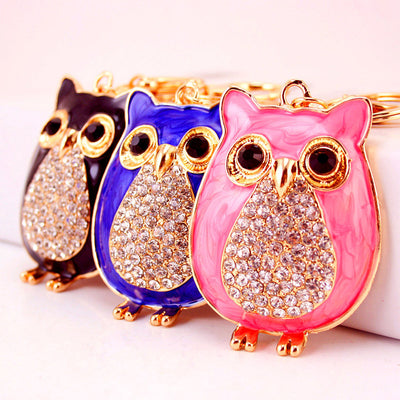 Pink, blue and black owl keychains displayed together with clear stone-covered bellies.