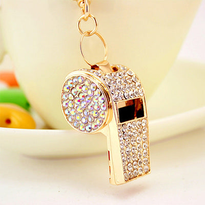 Close-up of a gold-tone whistle keychain covered in clear and iridescent rhinestones.