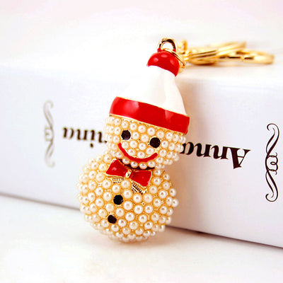 Close-up of a pearl-like beaded snowman with a red hat and bow tie beside a white box.