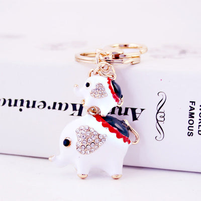 White elephant keychain with large and small charms, clear stone ears, and red and black back accents.