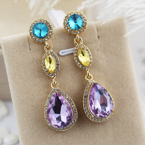 Side view of gold tone multicolor three stone long drop earrings
