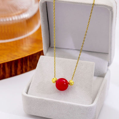 Gold red bead necklace with textured gold accents in gray jewelry box