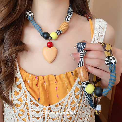 Heart pendant fabric bead necklace worn while hand holds matching strand without heart
