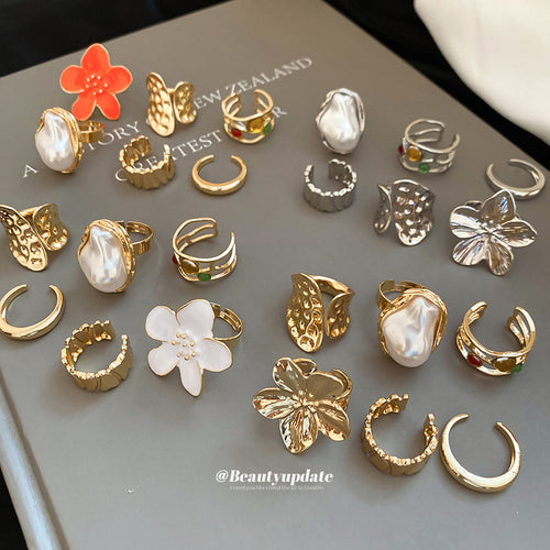 Assorted gold silver white and orange flower open rings on book cover