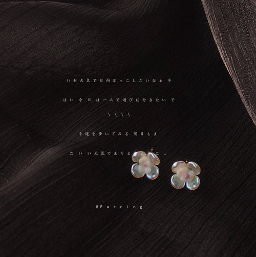 Iridescent four-petal flower studs on dark sheer fabric