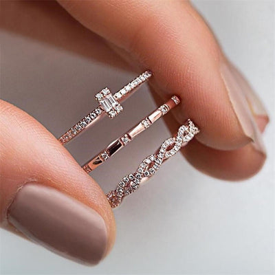 Three rose gold thin stackable rings held between fingers