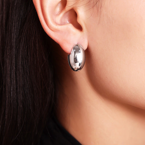 Silver steel polished egg-shaped oval hoop on ear close-up