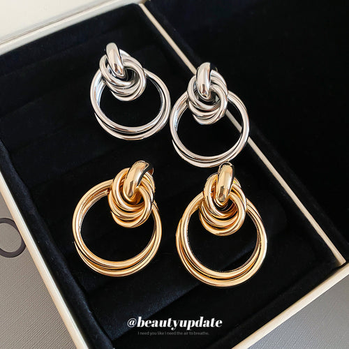 Interlocking smooth silver-tone loops gathered beneath a knot-like top shown in a front product view