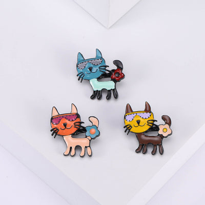 Front view of three cartoon cats in blue, coral, and yellow, each with playful accessories