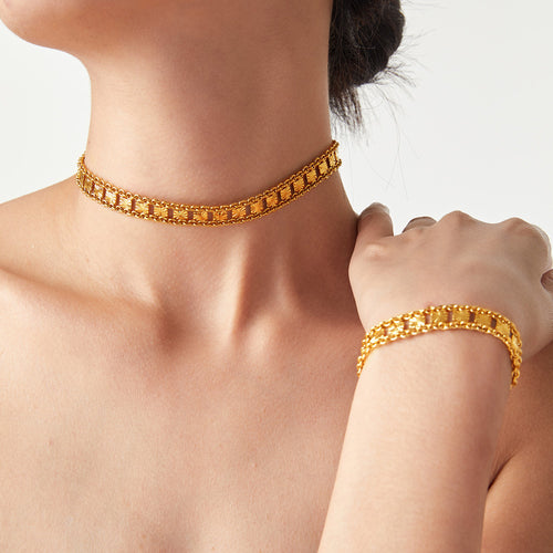 Model wearing gold starburst choker necklace and matching bracelet
