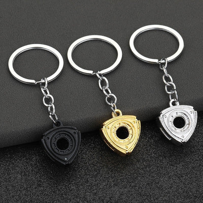 Three triangular rotary engine keychains in black, gold-tone, and silver-tone finishes.