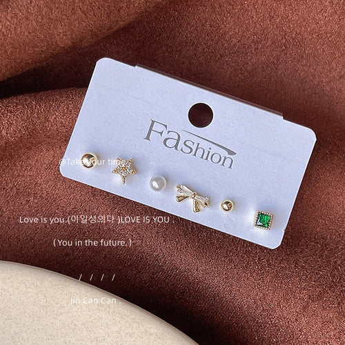 Six gold mini studs on white Fashion card on brown fabric