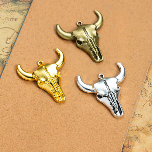 Gold tone, antique bronze, and silver tone bull skull charms together