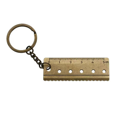 Bronze-tone mini ruler attached to a round key ring against white