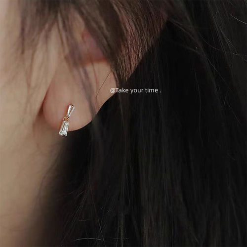 Silver-tone double-trapezoid clear-baguette mini studs shown worn on an ear.