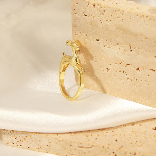 Gold deer ring standing on white fabric beside stone block