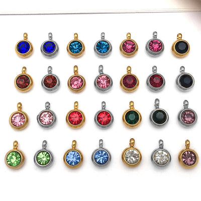 Metallic birthstone charms arranged on a light background
