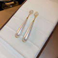 Long White Teardrop Pearl Earrings With Polished Metal Tone Details view 6