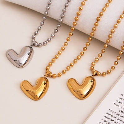 Gold and steel puffy heart ball chain necklaces on fabric