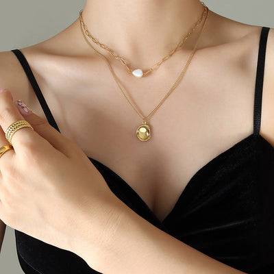 Woman in black top wearing gold double layer necklace with pearl and oval pendant