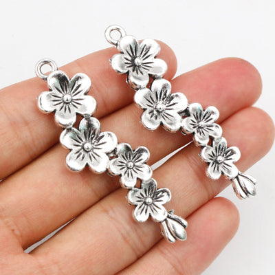 Assorted silver-tone plum blossom branch pendant charms for crafts arranged together in the main product view