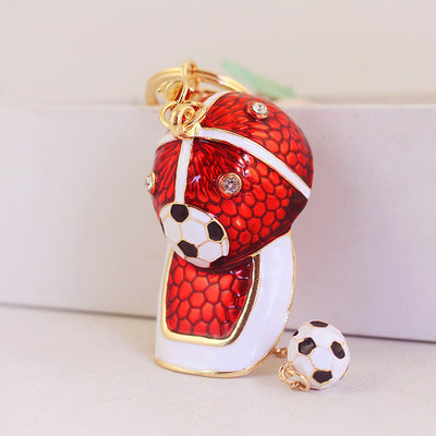 An upright red and white soccer cap charm is shown beside its dangling ball.