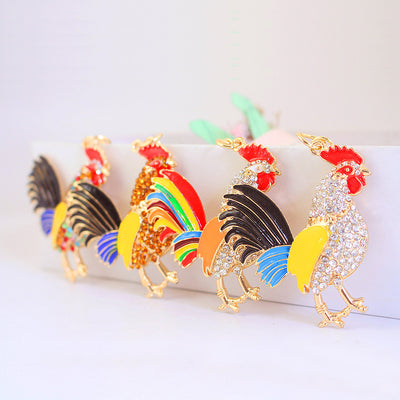 Five rooster charms displayed with rhinestones and assorted black, blue, yellow, orange, red, and rainbow accents.
